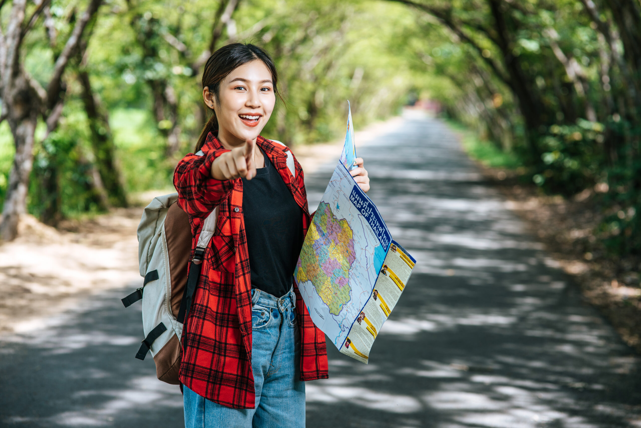 Female tourists stand and look at the map on the street and point their hands forward.