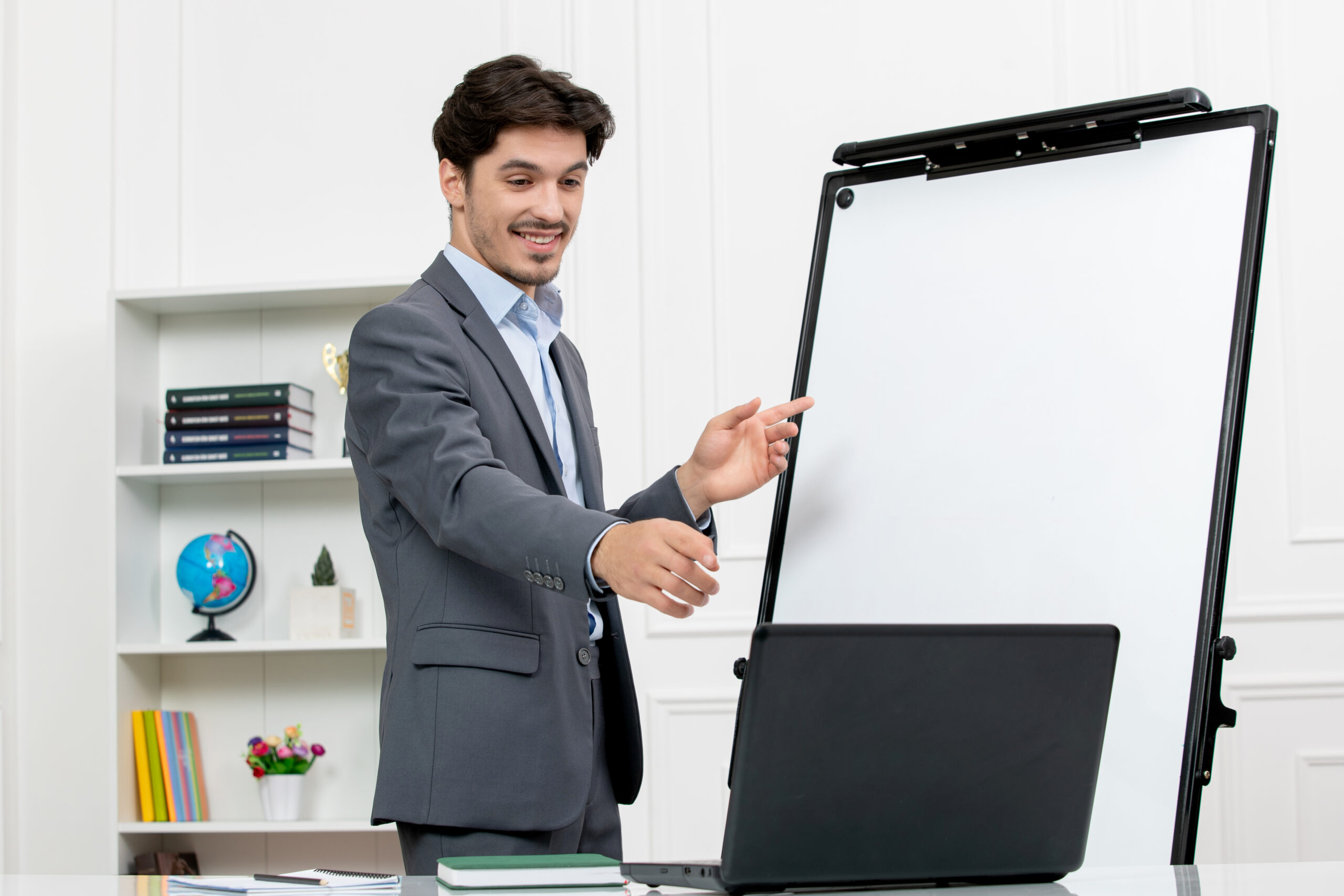 teacher-smart-instructor-grey-suit-classroom-with-computer-whiteboard-smiling-video-scaled